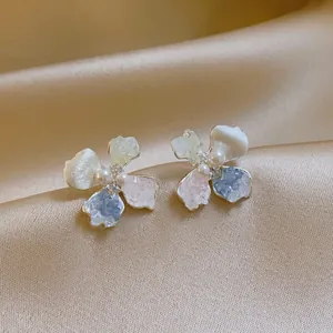 Close-up shot of elegant silver flower earrings with pearls and colorful frosted petals