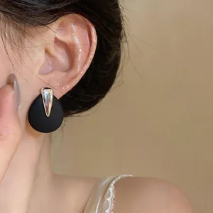 Macro view of minimalist black teardrop stud earrings with elegant silver accent