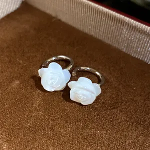 Close-up of elegant carved mother-of-pearl rose earrings with silver plating.