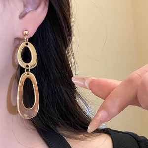 Close-up of elegant gold oval drop earrings worn by model, minimalist vintage style