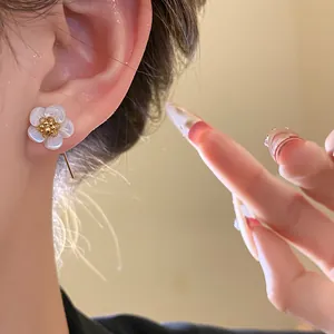Macro detail of elegant 18k gold plated flower earrings with white mother of pearl