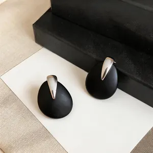 Detail shot of minimalist black drop earrings with elegant silver metallic accents.