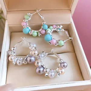 Gros plan détaillé de créoles serties de perles et de zircons dans une boîte à bijoux crème