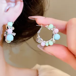 Gros plan de créoles avec perles colorées et zircons portées à l'oreille pour un style chic.
