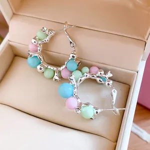 Vue détaillée de boucles d'oreilles créoles à perles colorées dans un écrin à bijoux chic.