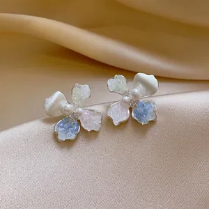 Close-up of elegant flower earrings with multi-colored crushed stone and pearls.