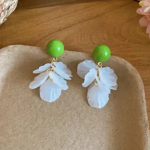 Boucles d'oreilles boules vertes avec glands de pétales blancs pour un look de plage chic.