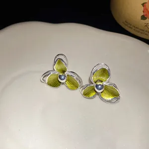 Vista macro di eleganti orecchini a fiore con finitura in smalto verde brillante