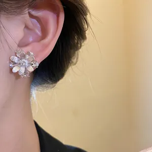 Primo piano di eleganti orecchini a lobo a forma di fiore in argento indossati da modella