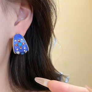 Dettaglio di orecchino a cerchio a C in smalto blu vintage con brillanti strass e perle