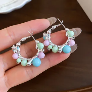 Vue détaillée des boucles d'oreilles créoles argentées avec perles pastel et zircons