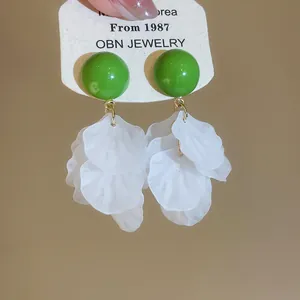 Détail de boucles d'oreilles vertes avec d'élégantes franges de pétales blancs translucides