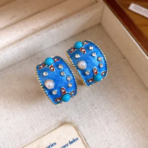 Dettaglio degli orecchini a cerchio a C in smalto blu con perle e cristalli vintage.