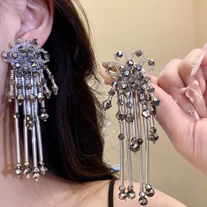 Détail des boucles d'oreilles fleurs en cristal bohème avec de longs glands métalliques.