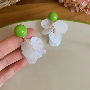 Gros plan de boucles d'oreilles à billes vertes avec élégantes pampilles en nacre blanche.