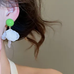 Détail de boucles d'oreilles boules vertes avec franges pétales en coquillage blanc