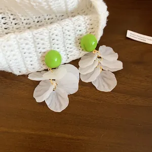Gros plan de boucles d'oreilles rondes vert vif avec pompons en pétales d'acrylique