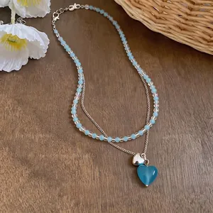Minimalist heart pendant necklace featuring blue and clear beads on a silver-tone chain