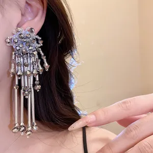 Gros plan d'élégantes boucles d'oreilles bohèmes à fleurs de cristal et franges