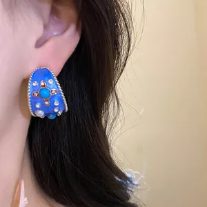 Vista dettagliata dell'orecchino vintage in smalto blu a forma di C con strass