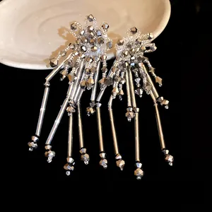 Détail de boucles d'oreilles bohèmes à longs glands avec cristaux facettés et tubes argentés