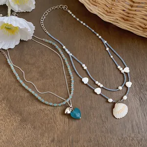Detailed view of beaded necklaces featuring seashell and heart charms on a wooden background