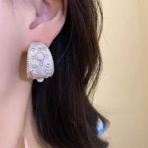 Primo piano di orecchino a perno vintage a C con smalto, strass e perla