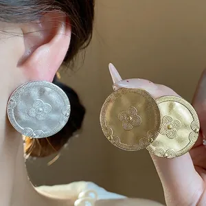 Elegant vintage matte gold and silver disk stud earrings with embossed floral pattern