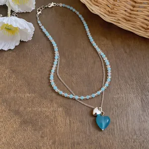 Elegant double-layered necklace featuring light blue beads and translucent heart pendants
