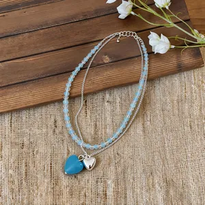 Detail of a minimalist double-layered necklace with blue beads and silver heart pendants