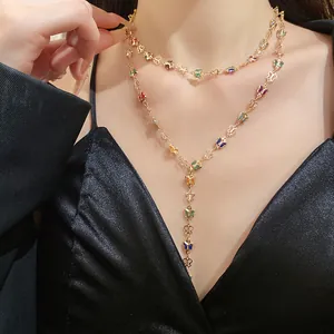 Detalle de collar en Y dorado con mariposas de cristal de colores en una modelo