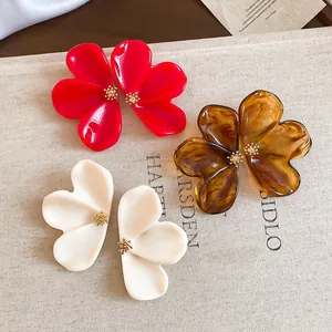 Detailed view of large resin flower earrings in red, amber, and off-white colors.
