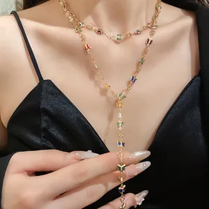Vista detallada de un collar en Y dorado con dijes de mariposa de vidrio de colores.