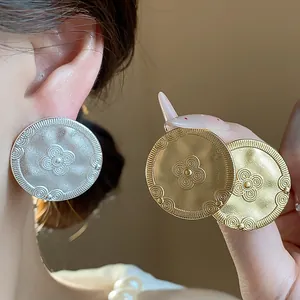Close-up of vintage 18K gold plated and silver matte round earrings with flower detail