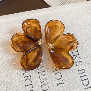 Detail view of brown marbled resin flower earrings with gold center accents.