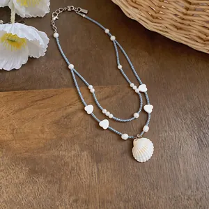 Close-up of double-layered beaded necklace with heart accents and seashell pendant