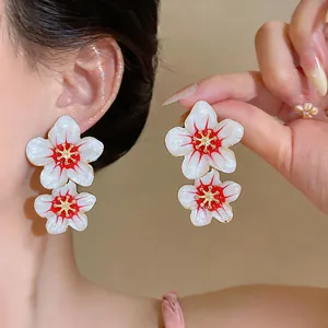 Close-up of elegant white and red enamel double flower drop earrings worn by model