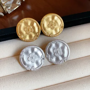 Macro view of vintage matte gold and silver stud earrings with embossed floral patterns