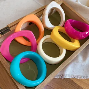 Collection of colorful irregular resin bangles in a rustic wooden display box.