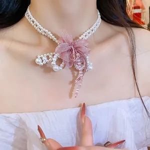 Detail view of pearl choker necklace featuring a pink chiffon flower and bead tassels.