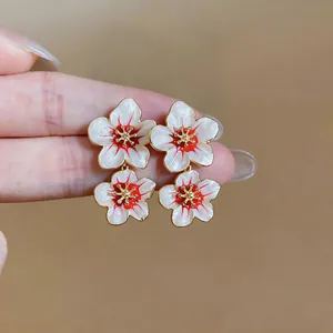 Close-up of elegant sweet style white and red enamel flower earrings with gold finish