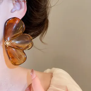 Close-up of a large amber resin flower earring with golden crystal center on model's ear