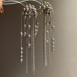 Detailed close-up of minimalist silver beaded tassel earrings with a metallic finish