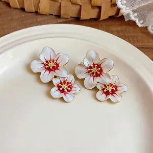 Close-up of elegant floral stud earrings with white and red oil-drop finish