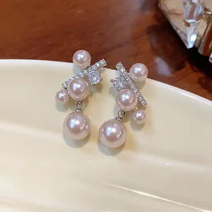 Dettaglio di eleganti orecchini con perle e zirconi su un vassoio ceramico