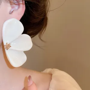 Detailed close-up showing an elegant oversized white resin flower earring worn by a model