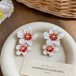 Macro detail showing sweet white and red enamel flower earrings with gold edges