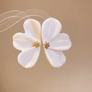 Detail shot of elegant white resin flower earrings with gold centers.
