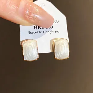 Boucles d'oreilles rectangulaires en résine avec bordure dorée et fini blanc perle.