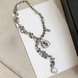 Detail showing rhinestone money bag pendant and pearl tassel on a long silver necklace.